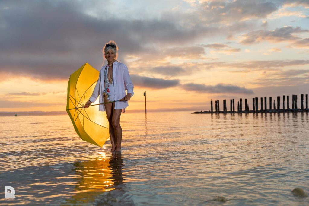 Heidi mit gelbem Regenschirm in der Hand, stehend auf dem Wasser.