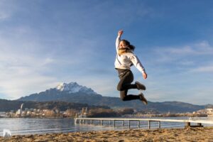 am Sandstrand Luftsprung von Corinne mit Pilatus und Schnee im Hintergrund