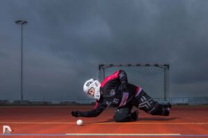 Laura in voller Unihockey-Dress auf den Ball am Boden zuhechtend