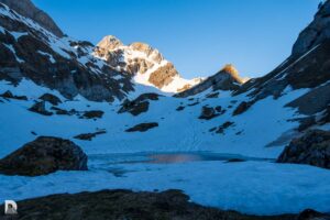 geschlossene Schneedecke mit teilweise gefrorenem Bergseelein und unsere Tour in der Morgensonne